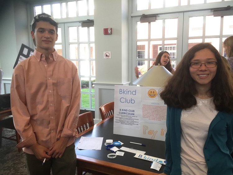 Two people standing next to a table with papers on it.