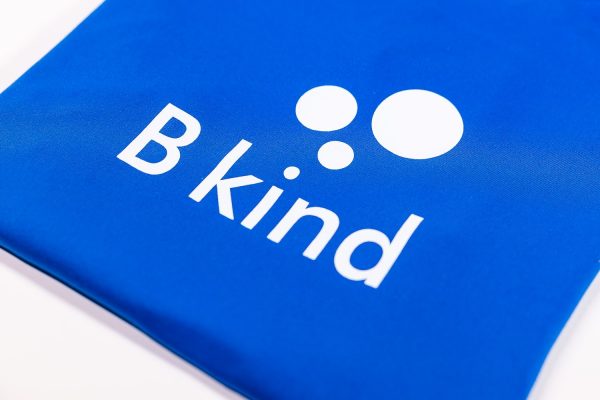 A close up of the b kind logo on a blue bag.